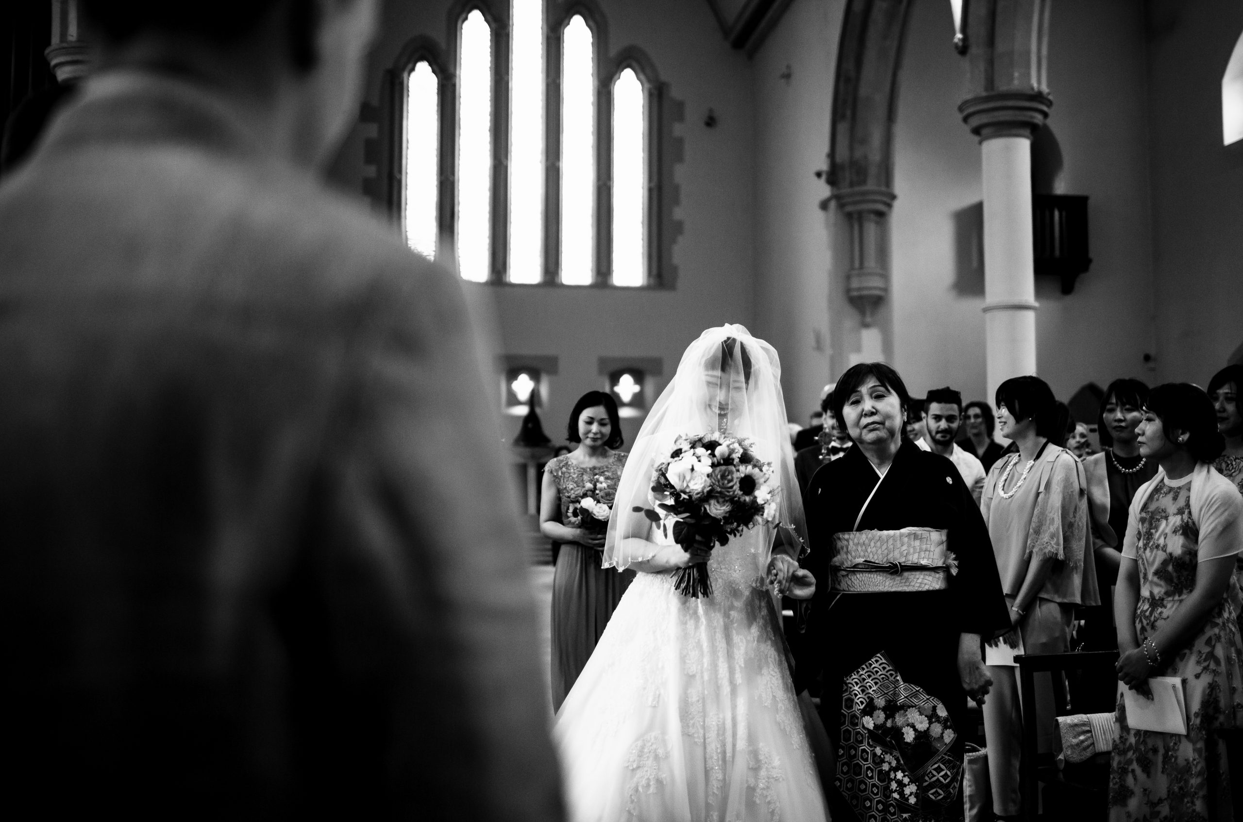 Bride is walking down the aisle with her mum looking at the groom