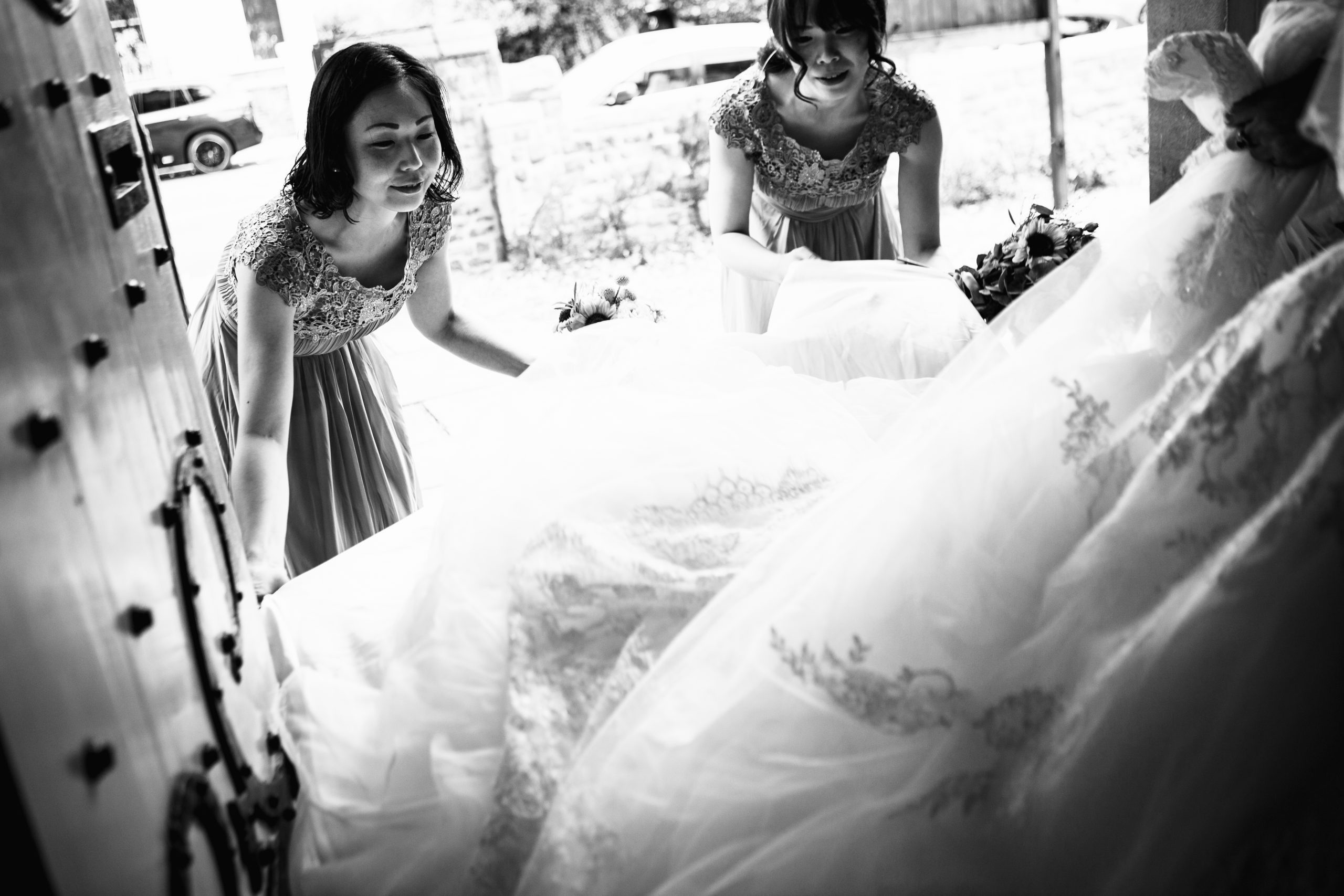 Two bridesmaids holding the end of the wedding dress