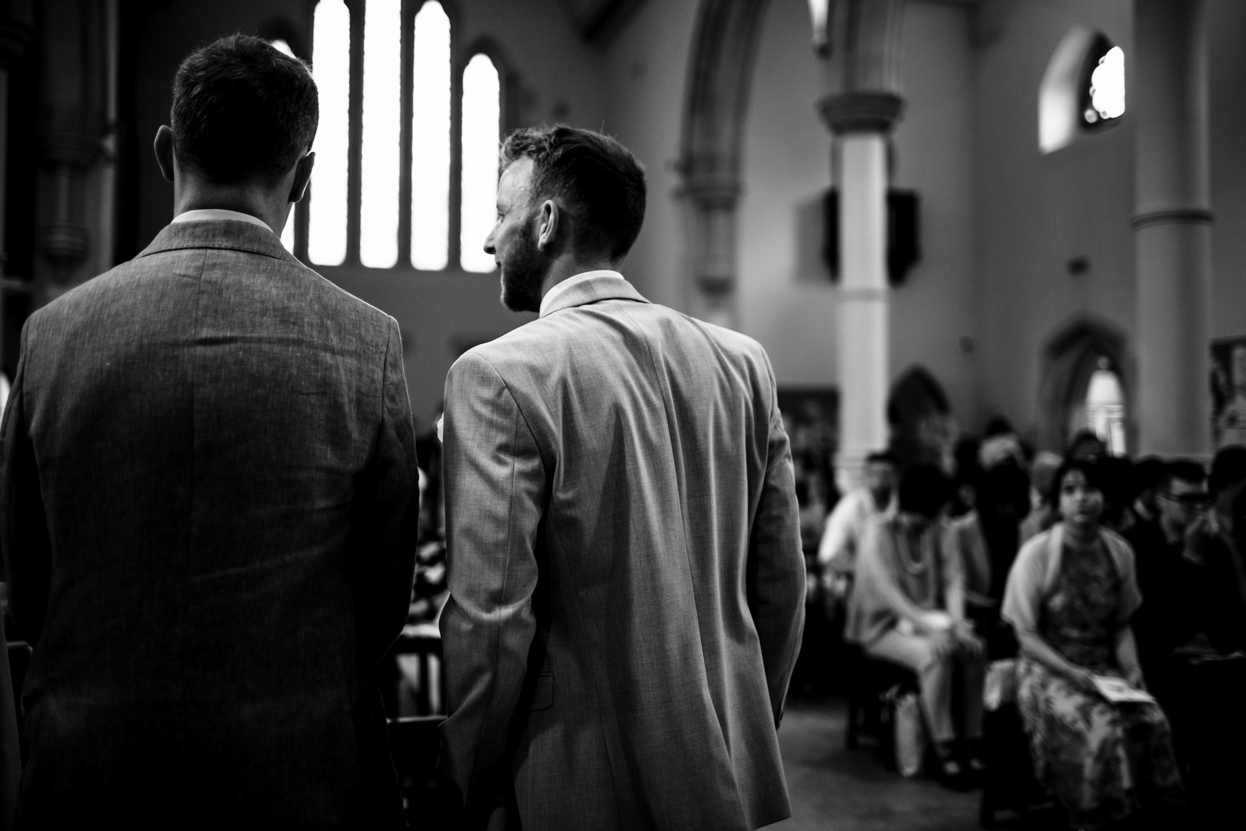 Groom standing next to his best man in church
