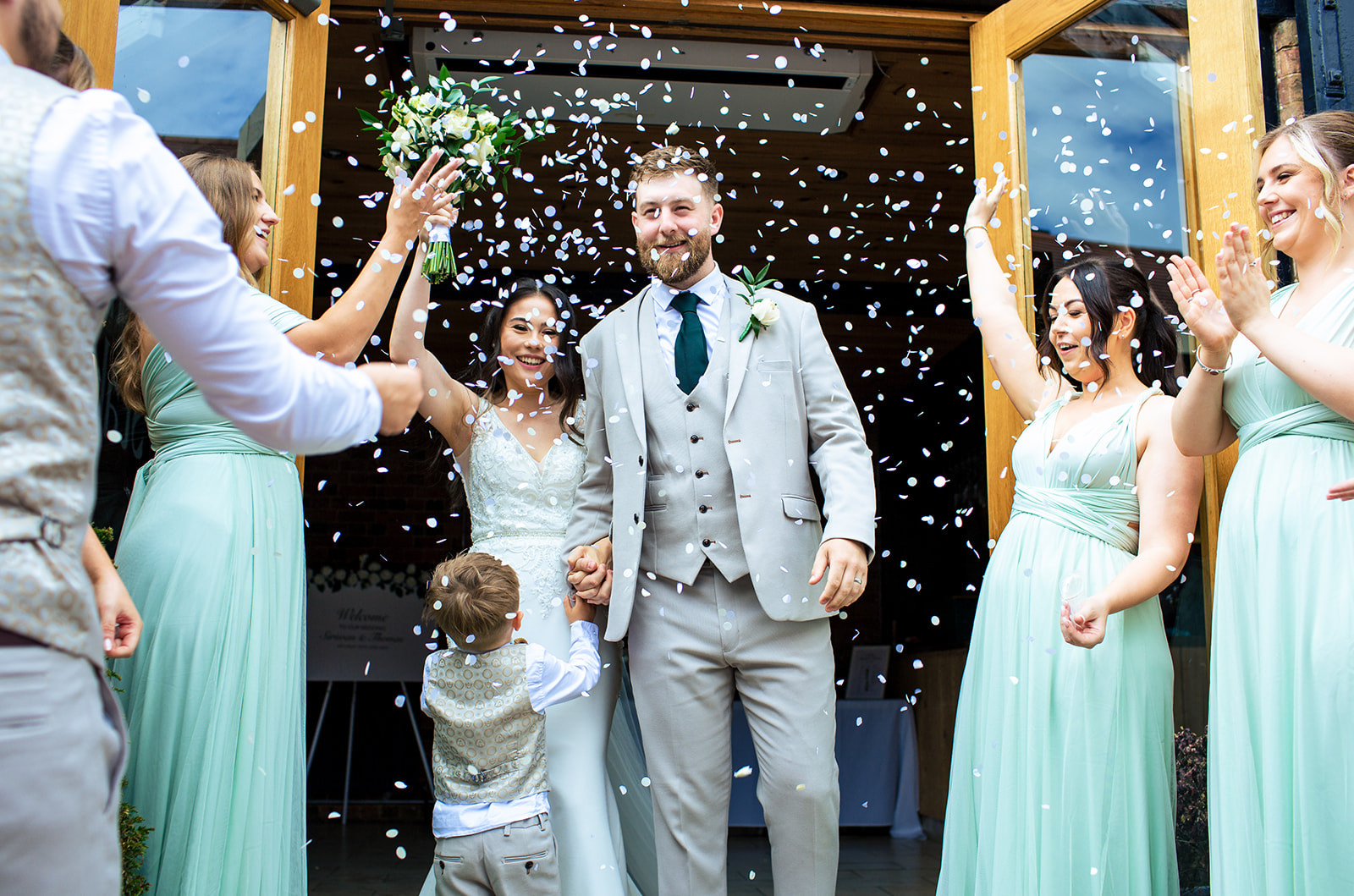 Wedding couple walking out with white confetti thrown at them